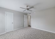 Thumbnail 17 of 61 - A room with a ceiling fan and carpeted floor.