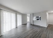 Thumbnail 19 of 61 - A spacious room with wooden floors and white walls.