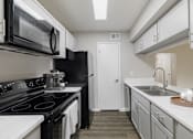 Thumbnail 7 of 29 - A kitchen with black appliances and white countertops.