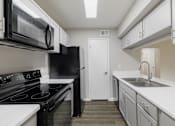 Thumbnail 12 of 61 - A kitchen with black appliances and white countertops.
