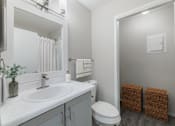 Thumbnail 9 of 29 - A bathroom with a white sink, toilet, and mirror.