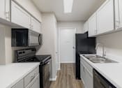 Thumbnail 9 of 61 - A kitchen with black appliances and white cabinets.