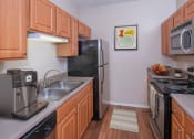 Thumbnail 5 of 21 - a kitchen with wood cabinets and stainless steel appliances
