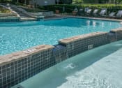 Thumbnail 12 of 21 - a swimming pool with a tiled wall and steps leading into the water