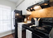 Thumbnail 4 of 35 - a kitchen with black appliances and white cabinets and a window