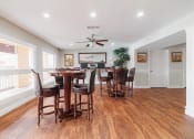 Thumbnail 19 of 32 - a dining room with a table and chairs and a kitchen with a ceiling fan