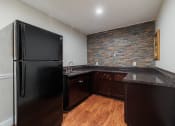 Thumbnail 23 of 32 - a kitchen with a black refrigerator and a stone wall