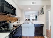 Thumbnail 5 of 54 - A kitchen with black appliances and white cabinets.