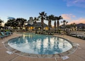 Thumbnail 33 of 43 - A large outdoor swimming pool surrounded by palm trees and lounge chairs.
