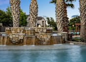 Thumbnail 36 of 43 - A pool with a waterfall and palm trees in the background.