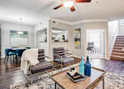 Thumbnail 3 of 21 - A living room with a wooden floor and a ceiling fan.