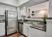 Thumbnail 1 of 21 - A kitchen with white cabinets and a stainless steel refrigerator.