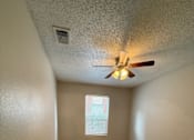 Thumbnail 8 of 10 - A room with a ceiling fan and wooden flooring.