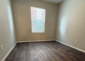 Thumbnail 5 of 10 - A room with wooden flooring and a window with blinds.