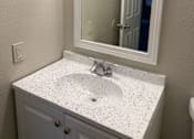 Thumbnail 7 of 10 - A bathroom sink with a mirror above it.