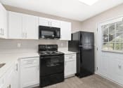 Thumbnail 5 of 16 - a kitchen with white cabinets and black appliances