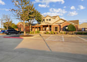 Thumbnail 15 of 16 - A parking lot in front of a building with a car parked in the lot.