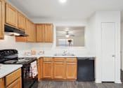 Thumbnail 3 of 16 - A kitchen with wooden cabinets and a black stove top oven.