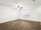 Thumbnail 6 of 16 - A room with a ceiling fan and wooden flooring.