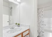 Thumbnail 9 of 16 - A bathroom with a sink, mirror, and shower.