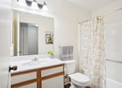 Thumbnail 7 of 16 - A bathroom with a white sink, toilet, and shower curtain.