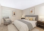 Thumbnail 5 of 23 - A bedroom with a bed, chair, and two lamps.