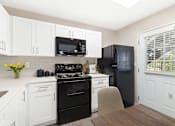 Thumbnail 3 of 23 - A kitchen with black appliances and white cabinets.