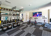 Thumbnail 12 of 25 - a gym with weights and exercise equipment and a television