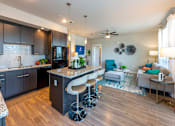 Thumbnail 6 of 25 - a kitchen with a bar and a living room with a couch