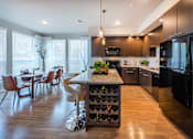 Thumbnail 5 of 25 - a kitchen with a bar and a dining room with a table and chairs