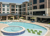 Thumbnail 19 of 25 - a large swimming pool with lounge chairs in front of an apartment building
