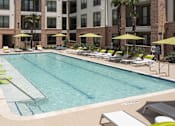 Thumbnail 20 of 25 - a swimming pool with lounge chairs and a building in the background