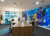 Thumbnail 15 of 25 - an office with a large desk with two computers and a wall with a blue mural
