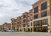 Thumbnail 23 of 25 - a large brick building with cars parked in front of it
