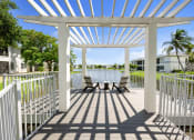 Thumbnail 23 of 41 - a patio with a pergola and chairs overlooking a body of water