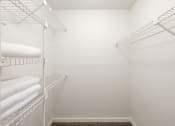 Thumbnail 30 of 41 - a walk in closet with white walls and shelves and white towels