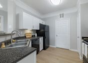 Thumbnail 28 of 39 - A kitchen with black appliances and white cabinets.