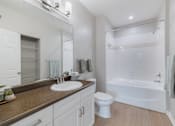 Thumbnail 30 of 39 - A white bathroom with a brown counter top and a white toilet.