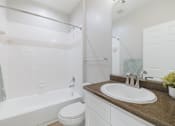 Thumbnail 32 of 39 - A white toilet sits next to a white bathtub in a bathroom.