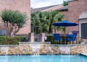 Thumbnail 31 of 37 - a swimming pool with chairs and an umbrella in front of a house