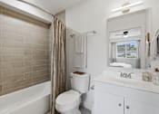 Thumbnail 21 of 41 - A white bathroom with a toilet, sink, and bathtub.