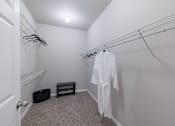 Thumbnail 14 of 42 - A white robe is hanging on a rack in a small, carpeted room.