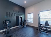 Thumbnail 28 of 42 - A gym with a wall that says "make it happen" and a row of exercise equipment.