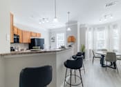 Thumbnail 6 of 42 - A kitchen with a bar area and a dining table with chairs.