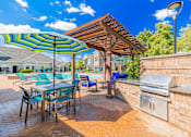 Thumbnail 37 of 42 - A patio with a table and chairs under a striped umbrella.