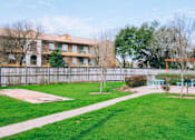 Thumbnail 27 of 28 - a yard with a picnic area and a fence with an apartment building in the background