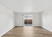 Thumbnail 22 of 38 - A room with wooden floors and a white wall with a doorway leading to a balcony.