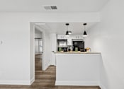 Thumbnail 20 of 38 - A kitchen with white walls and a wooden floor.