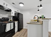 Thumbnail 19 of 38 - A kitchen with black appliances and a marble countertop.