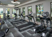 Thumbnail 18 of 28 - A gym with treadmills, elliptical machines, and a weight machine.